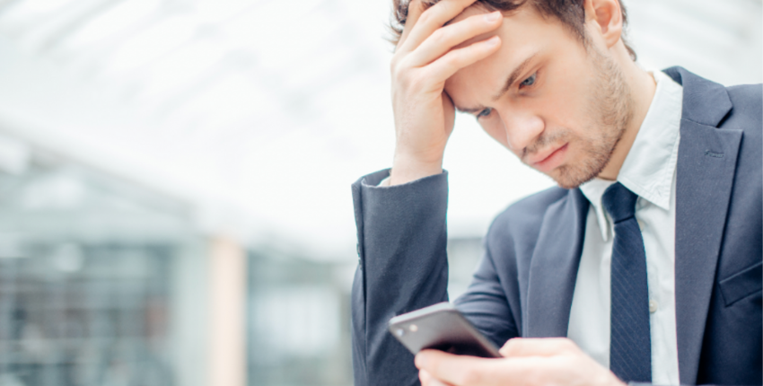 頭を抱えながらスマホ操作する男性