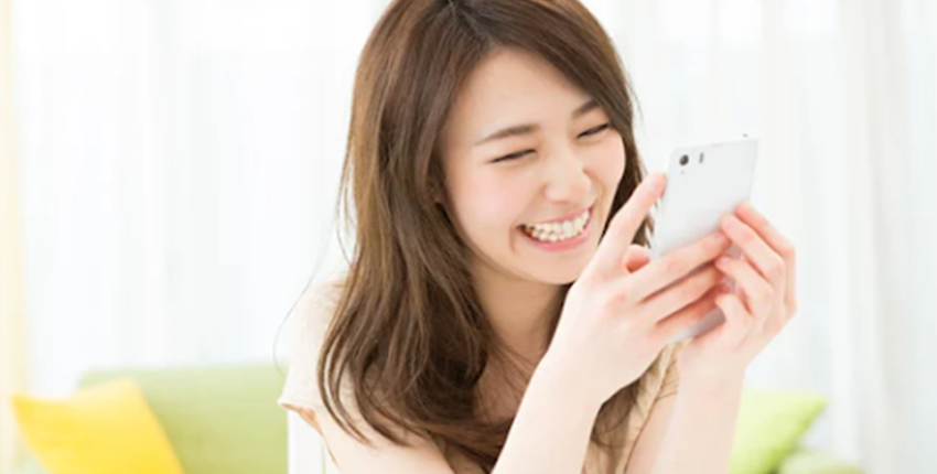 イオンモバイルの料金プランに満足して笑顔でスマホを使う女性