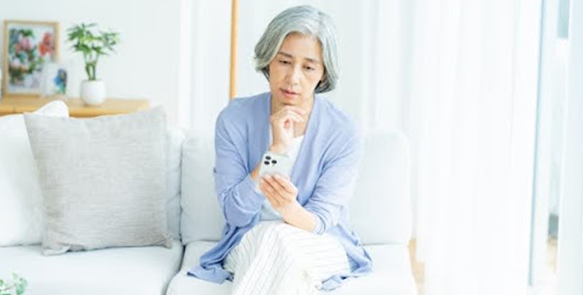 スマホをみて不安そうな表情をうかべるシニア女性