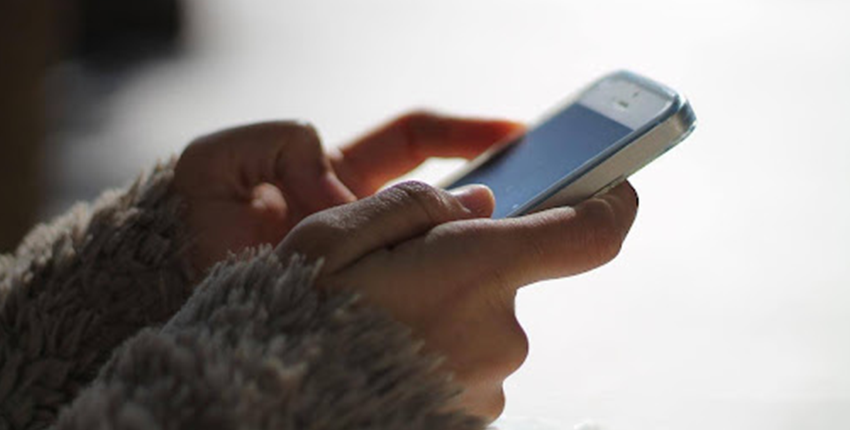iPhoneが動作しなくなり、両手で操作する女性