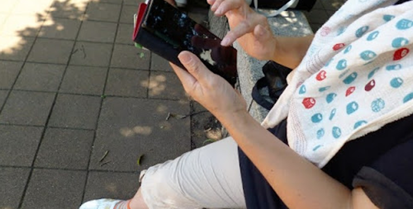 日陰でスマホ操作をする女性