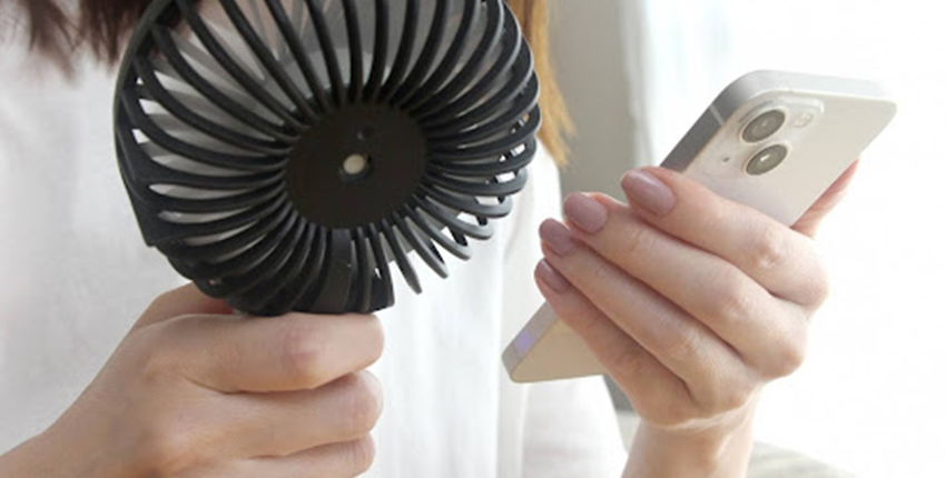 ハンディファンを片手にスマホ操作をする女性